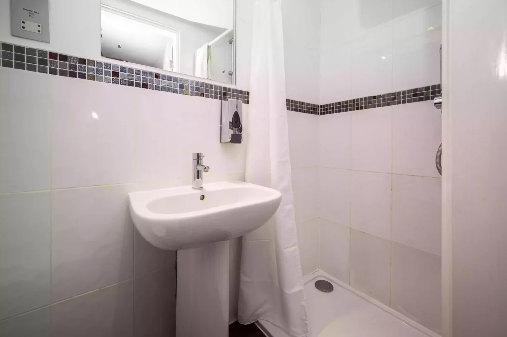 Small bathroom at the Mentone Hotel with a pedestal sink and shower area