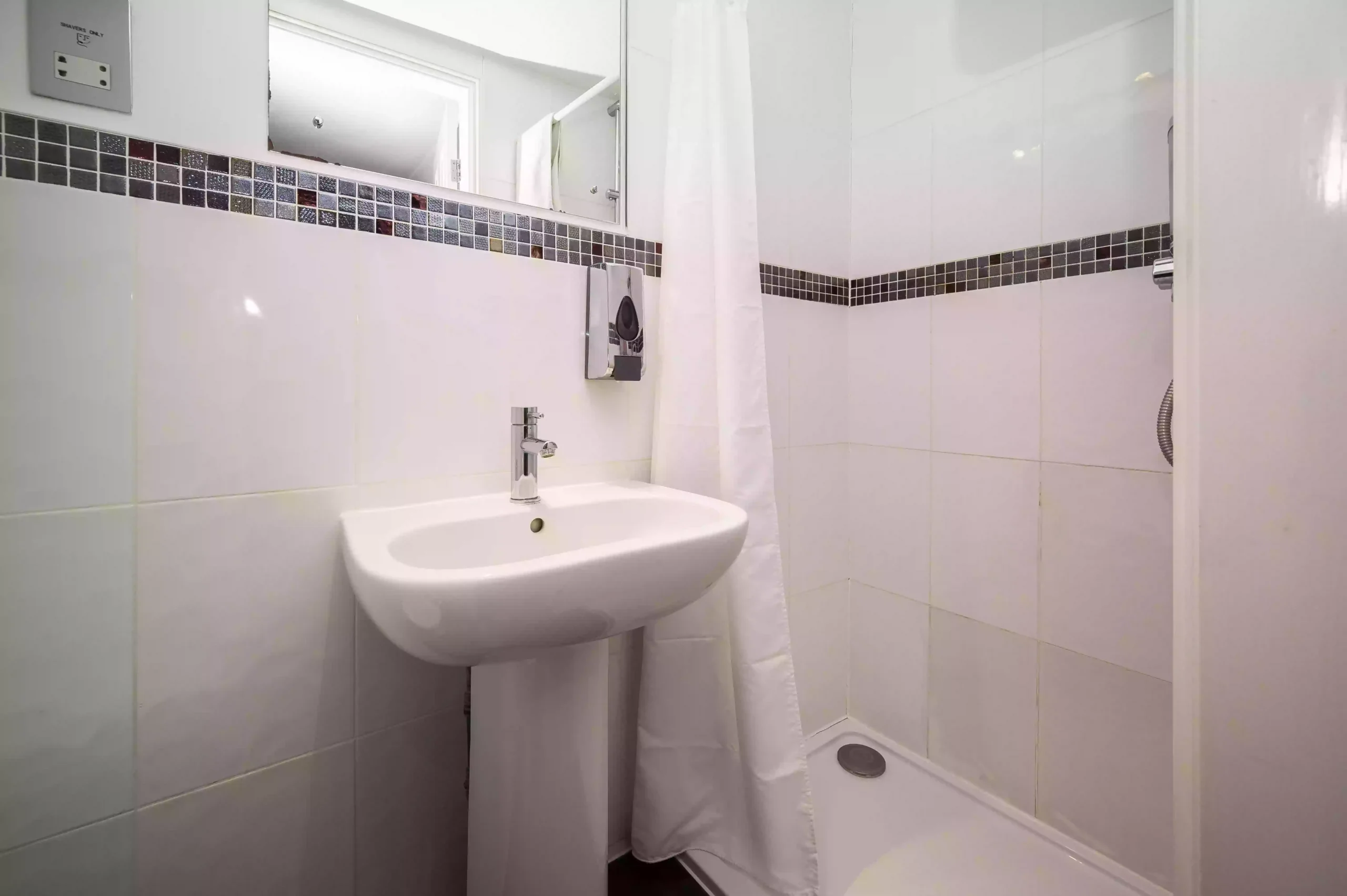 Small bathroom with a pedestal sink and shower area in the Double En-Suite Room at the Mentone Hotel