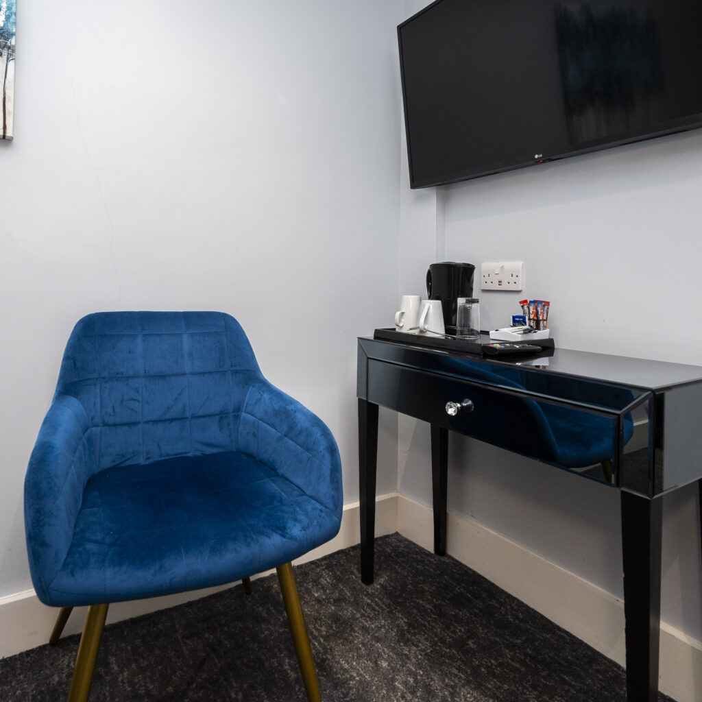 A chair beside a black desk and mounted flat-screen TV at the Mentone Hotel