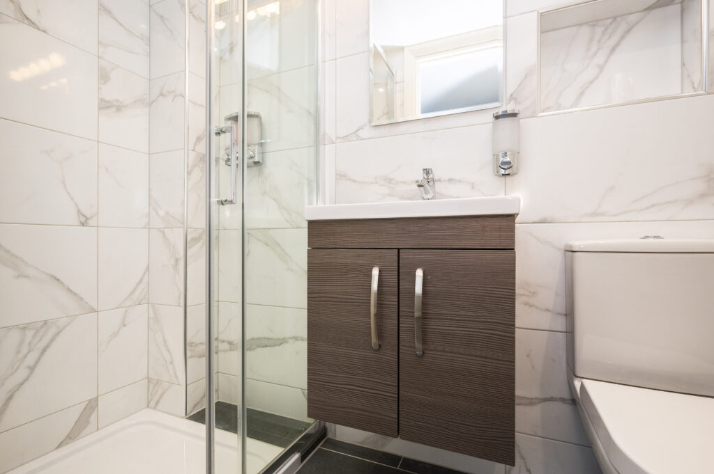 Modern bathroom with a glass shower door and wooden vanity at the Mentone Hotel