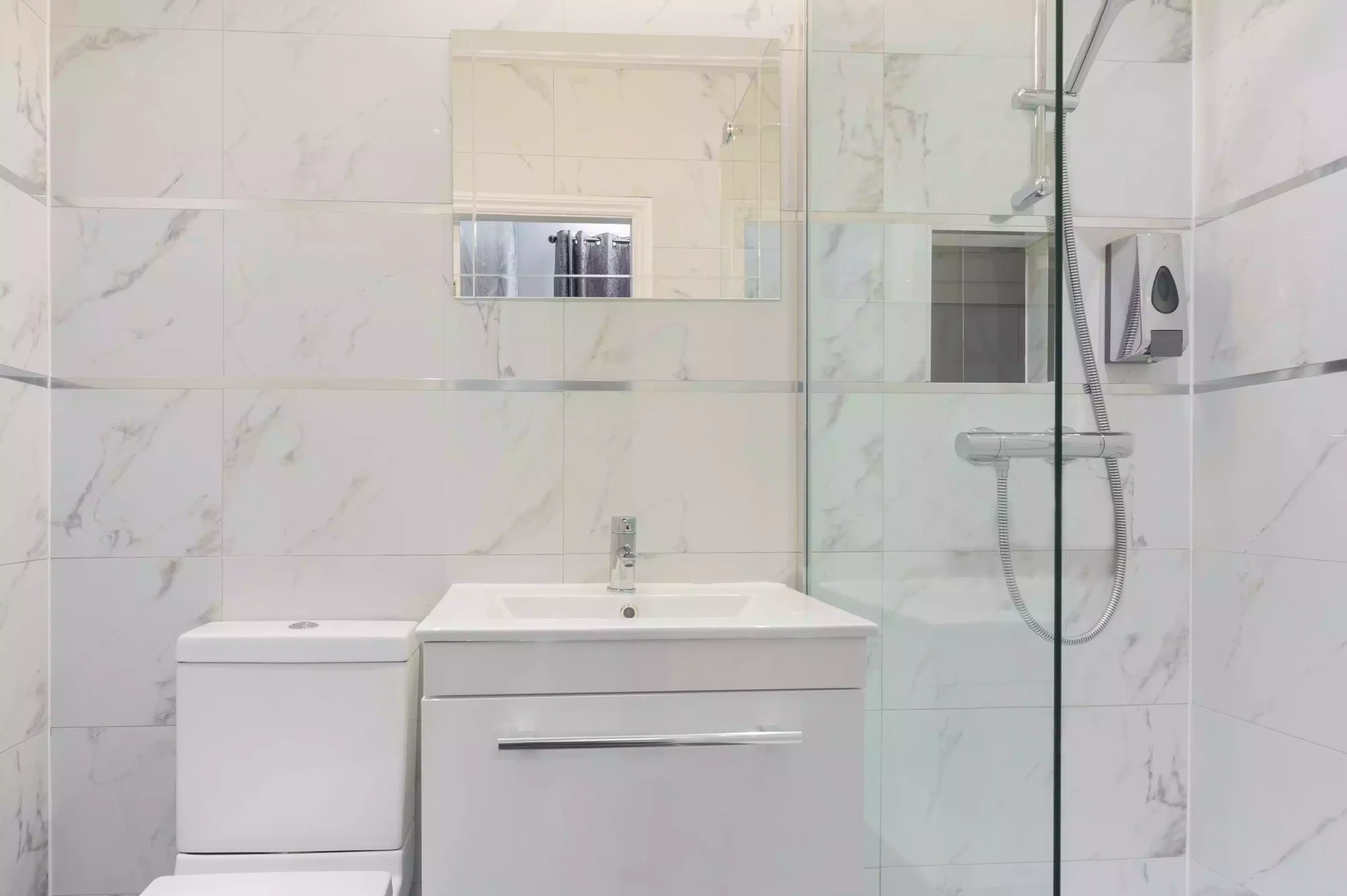 Modern bathroom at Mentone Hotel featuring a toilet, sink vanity, mirror, and glass-enclosed shower