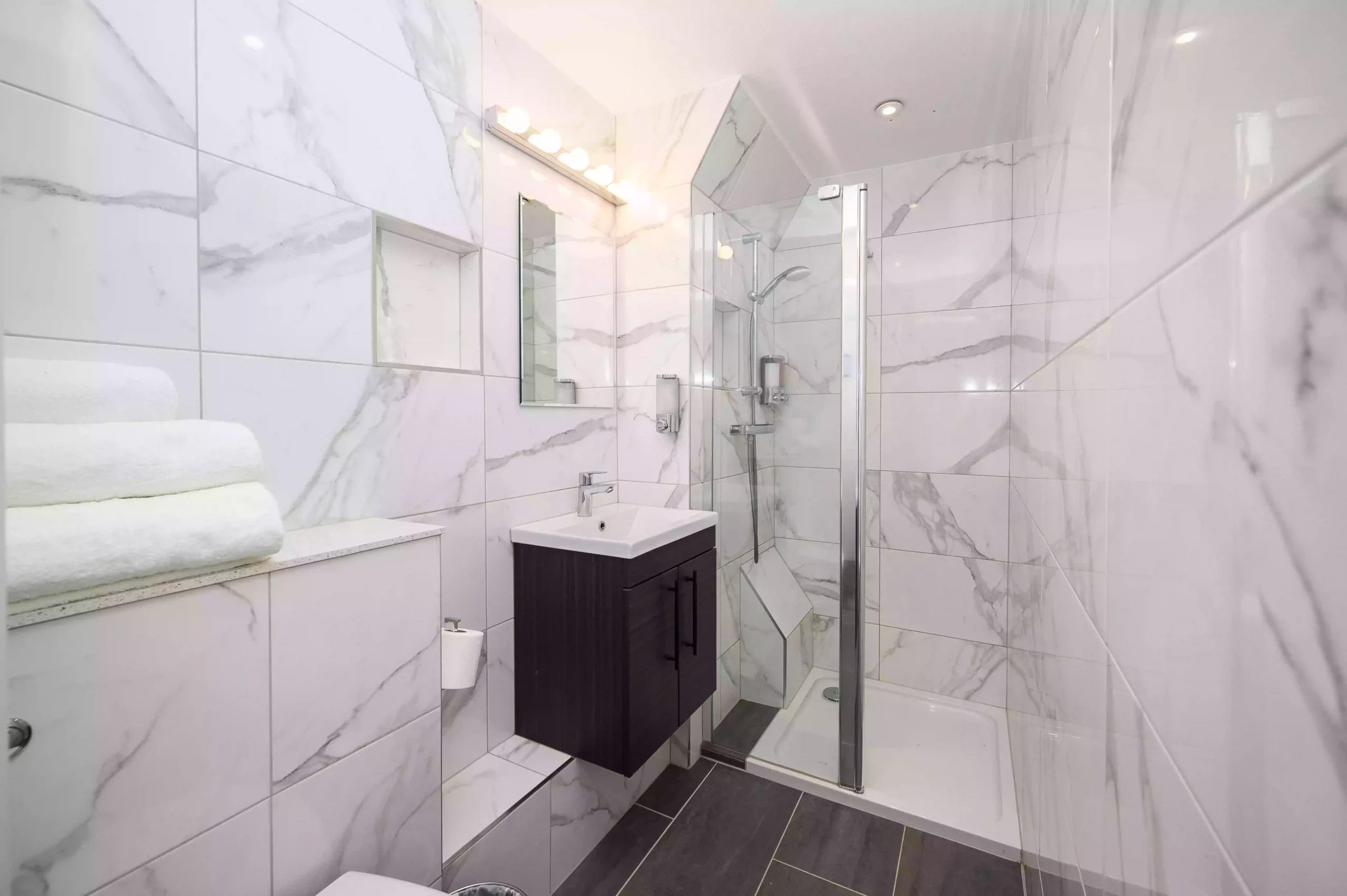 Modern bathroom at the Mentone Hotel with a wall-mounted sink and a glass-enclosed shower