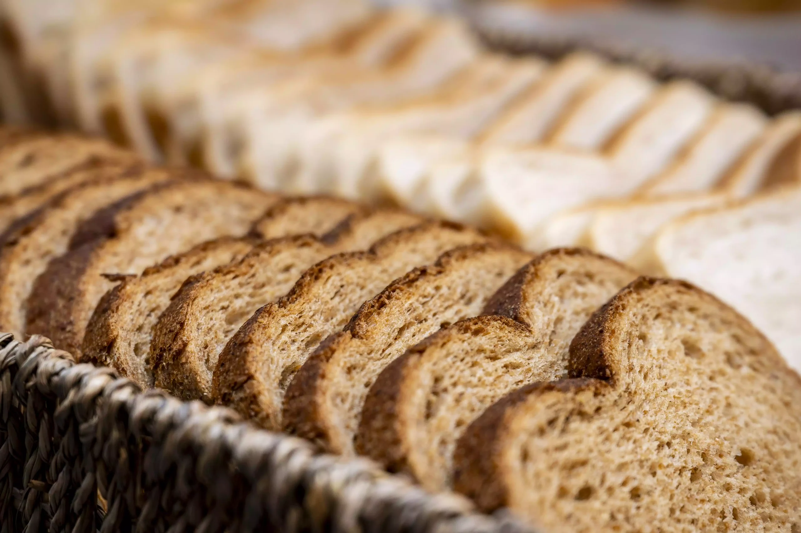 Slices of brown and white bread neatly arranged in a woven basket