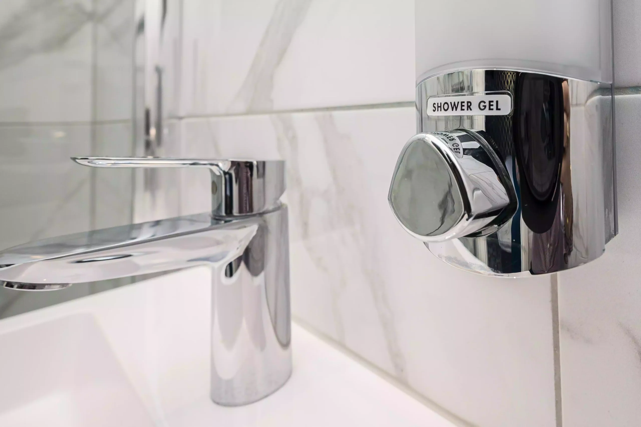 Faucet positioned beside a shower gel dispenser at the Mentone Hotel