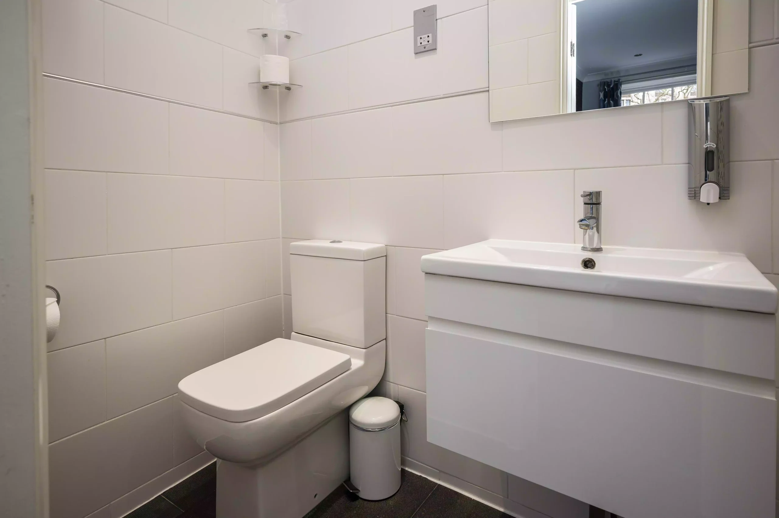 Modern bathroom with a toilet, sink, and mirror at Mentone Hotel