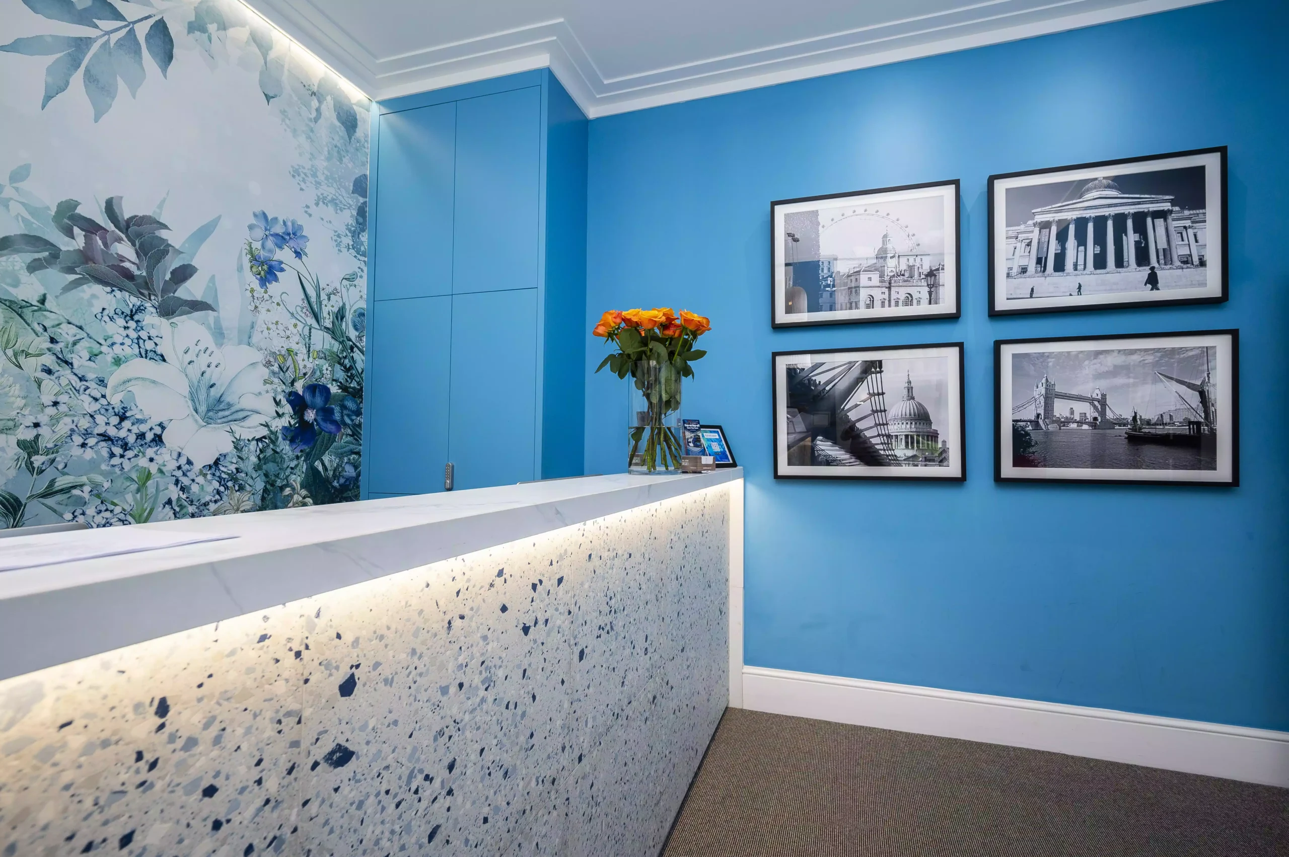 Hotel reception area with a counter, blue walls, and framed black-and-white photos at the Mentone Hotel