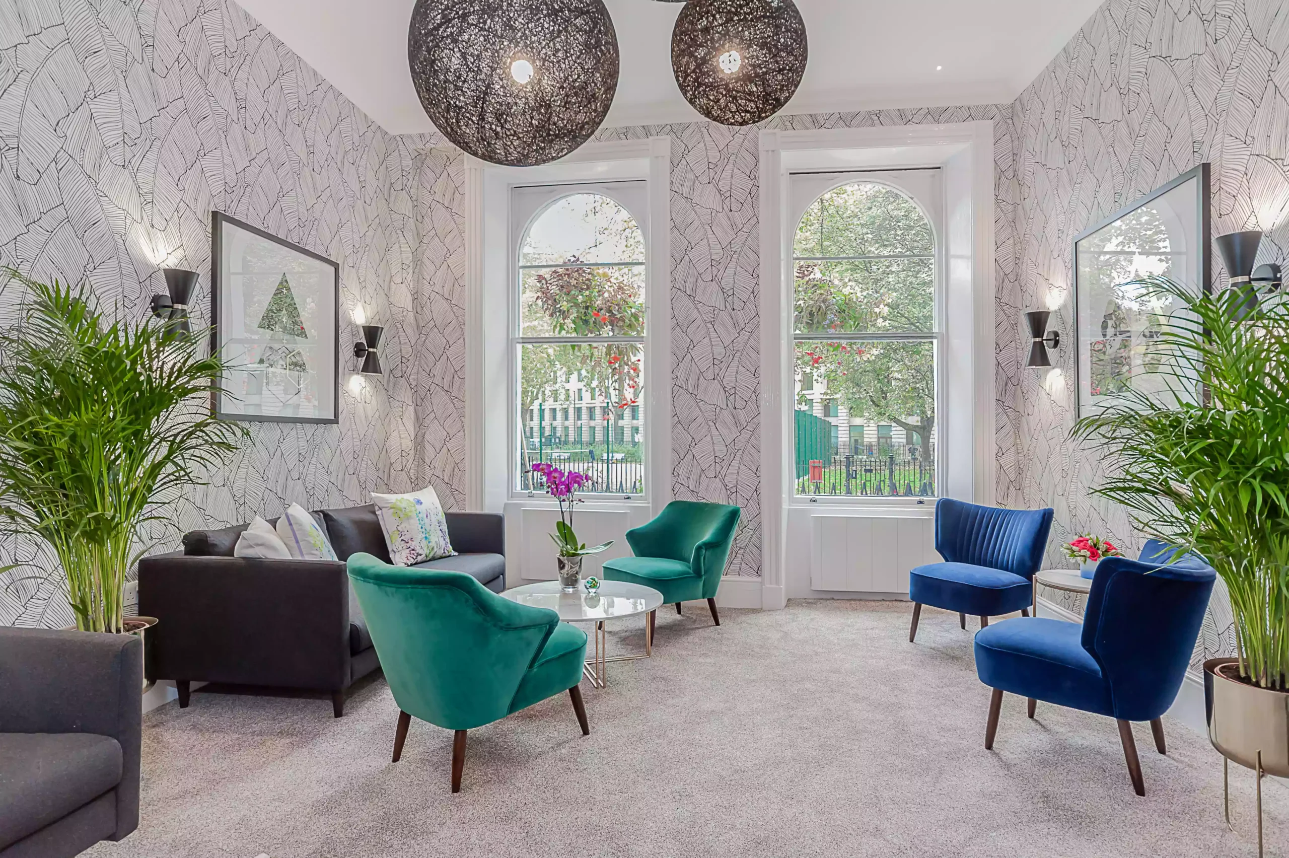 Mentone Hotel's waiting room or lobby with chairs, two large windows, and potted plants