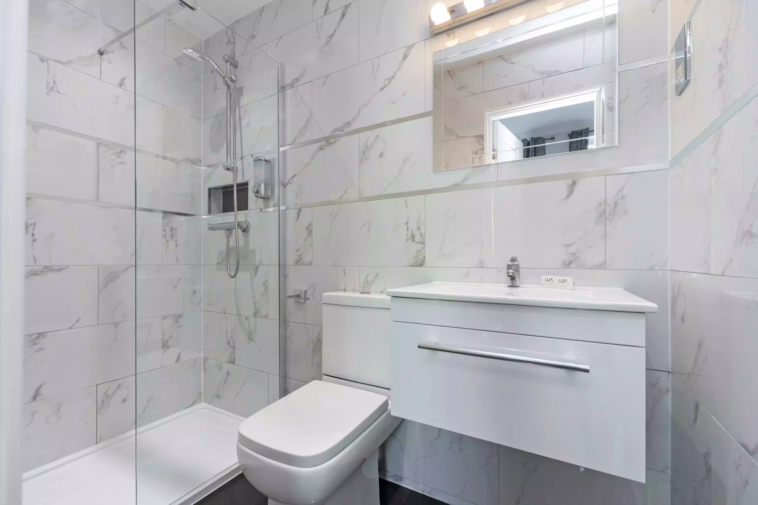 A modern bathroom at the Mentone Hotel with a shower, toilet, and white vanity